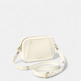 A ecru crossbody bag in a simple box shape with adjustable strap and gold hardware