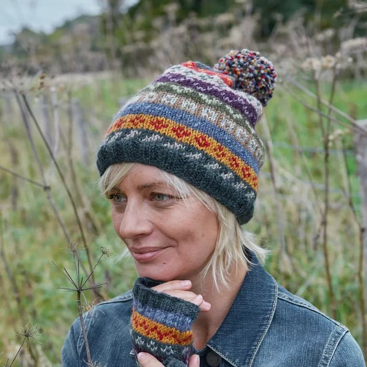 A multicolour neutral tone knitted hat with fair isle pattern and pompom on model