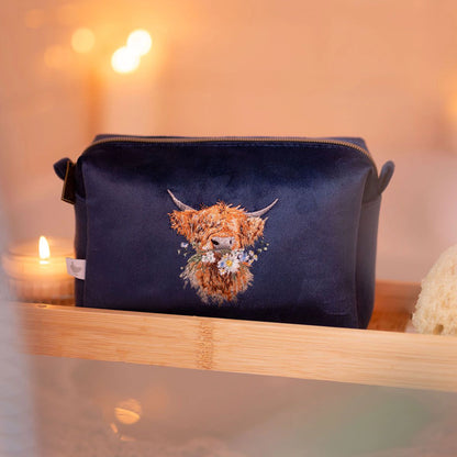 Navy blue make up bag with embroidered Highland cow design and zip top lifestyle