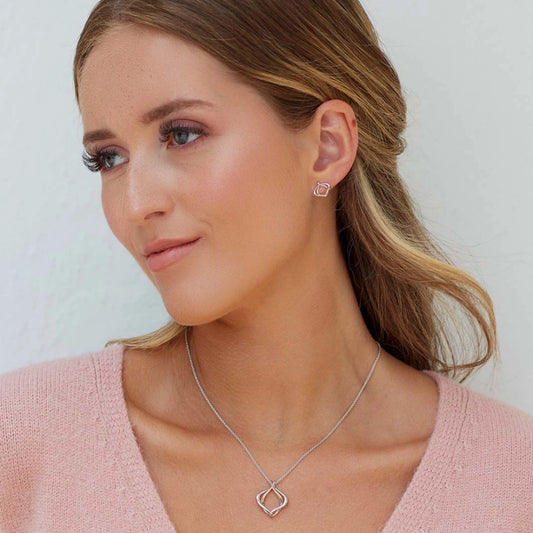Model wearing a pendant with two entwined organic diamond shapes with one in rose gold
