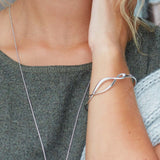 Model wearing a bangle with a silver twist marquise shaped hinged clasp