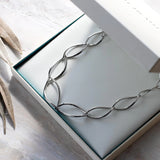 A necklace of silver links in a simple twist marquise shapes with a toggle clasp in a box