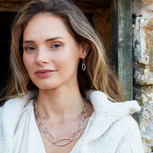 Model wearing a necklace of silver links in a simple twist marquise shapes with a toggle clasp