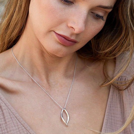 Model wearing a silver pendant in a simple twist marquise shape