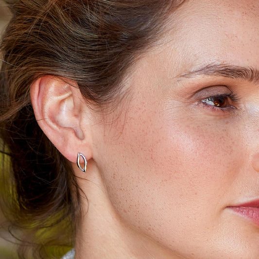 Model wearing a pair of silver earrings in a simple twist marquise shape