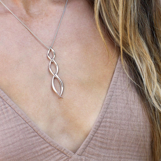 Model wearing a pendant featuring three linked marquis twists in silver