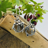Posed round silver bird nest earrings with bird & leaf design and a flower with a gold centre on hook fittings 