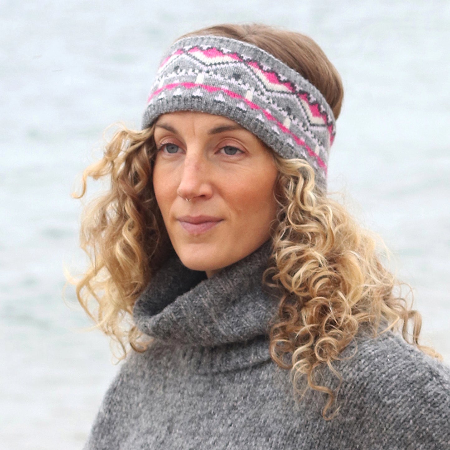 Model wearing knitted fair isle patterned headband in grey and pink