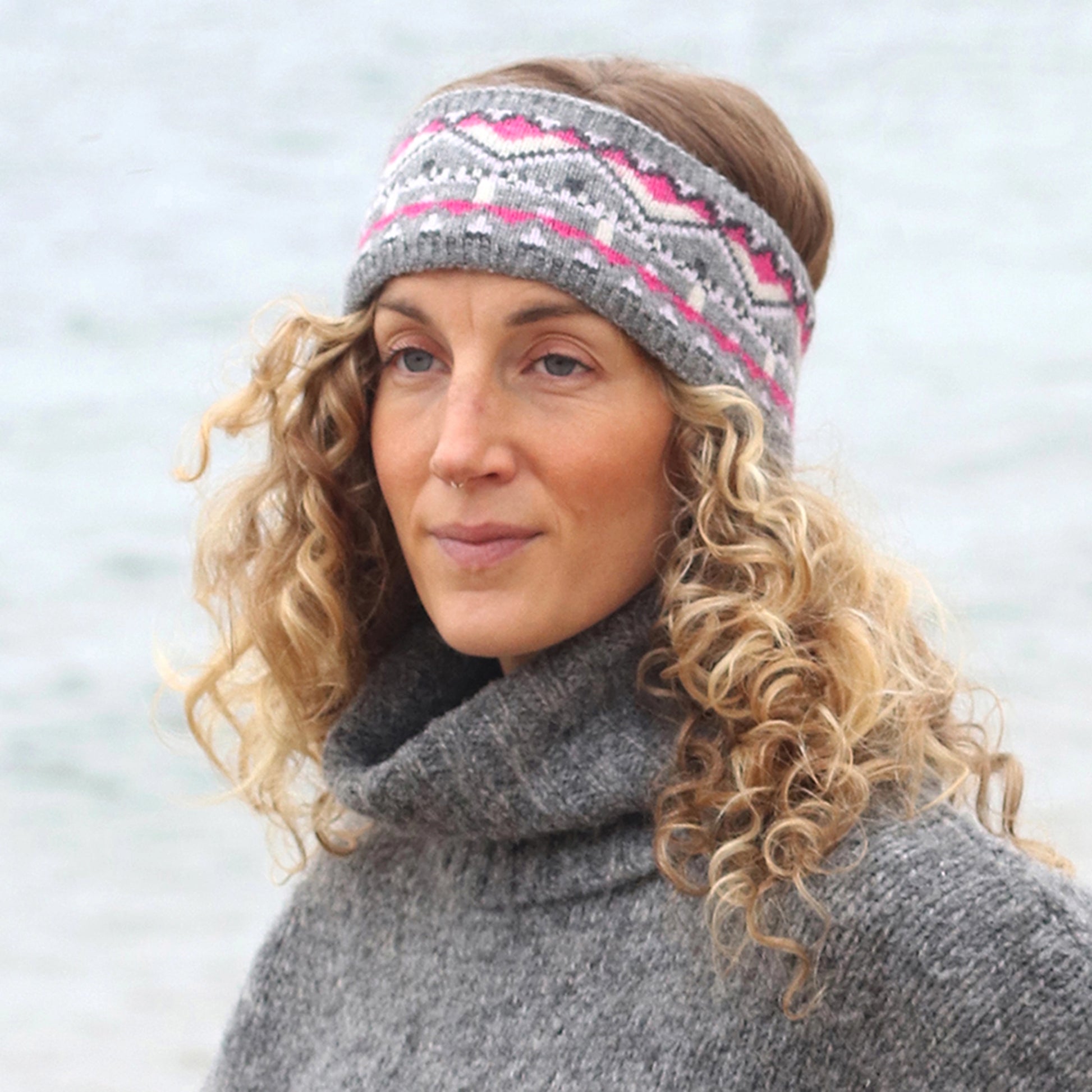 Model wearing knitted fair isle patterned headband in grey and pink