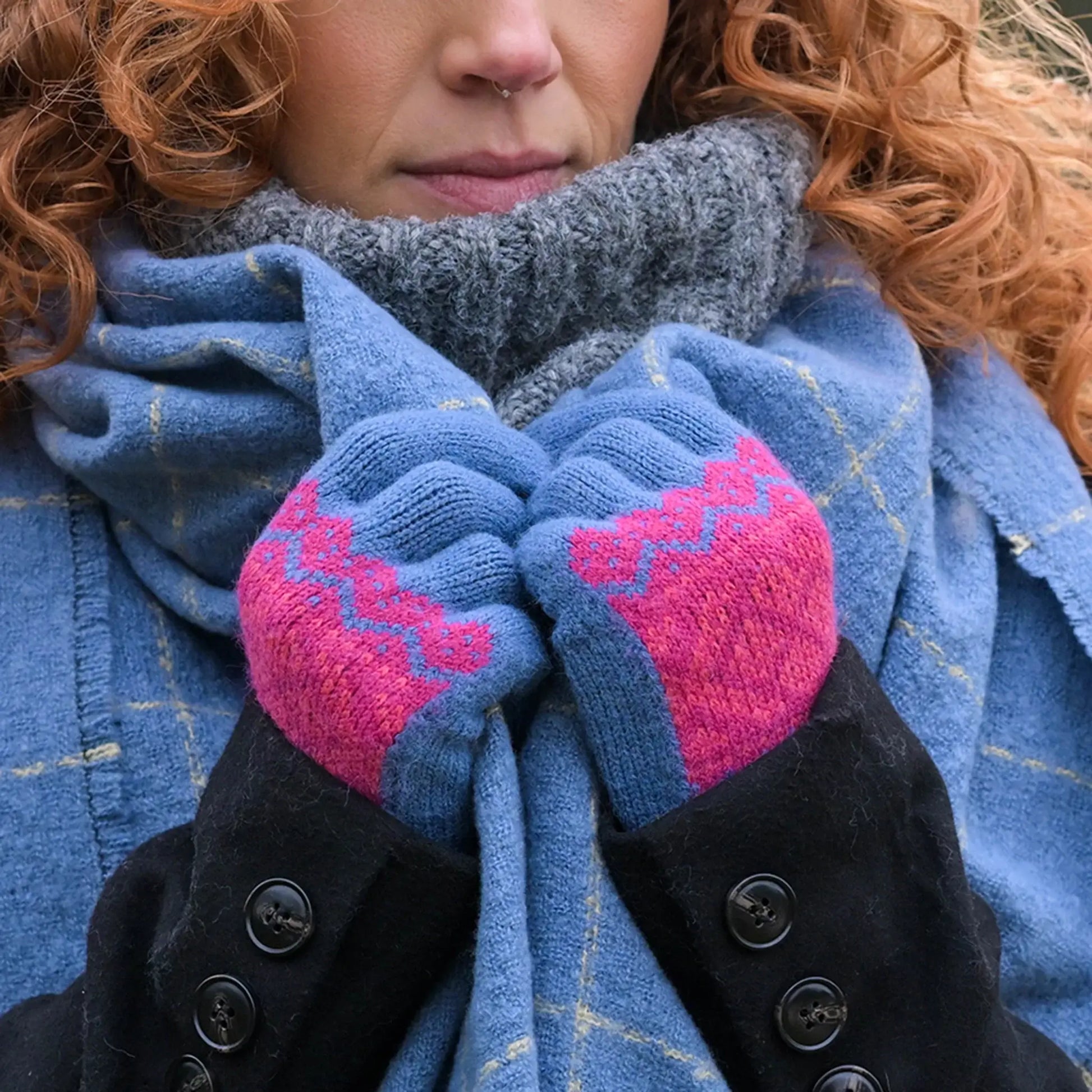 Model wearing blue knitted gloves with a red/pink fair isle style pattern