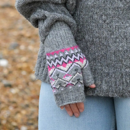 Model wearing pair of grey fingerless gloves with fair isle patterns in pink