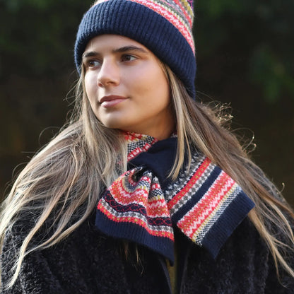 Model wearing fair Isle patterned knitted pull through scarf in navy blue and rust colours