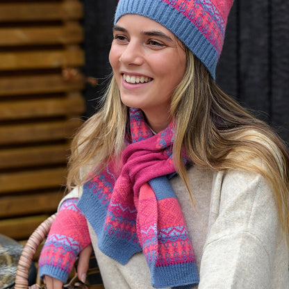 Model wearing bright pink and blue knitted pull through scarf with fair isle pattern