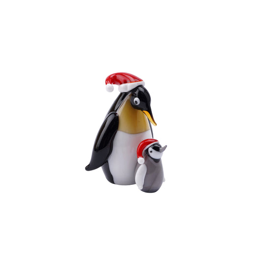 A glass figurine ornament with a parent and baby penguin in Santa hats