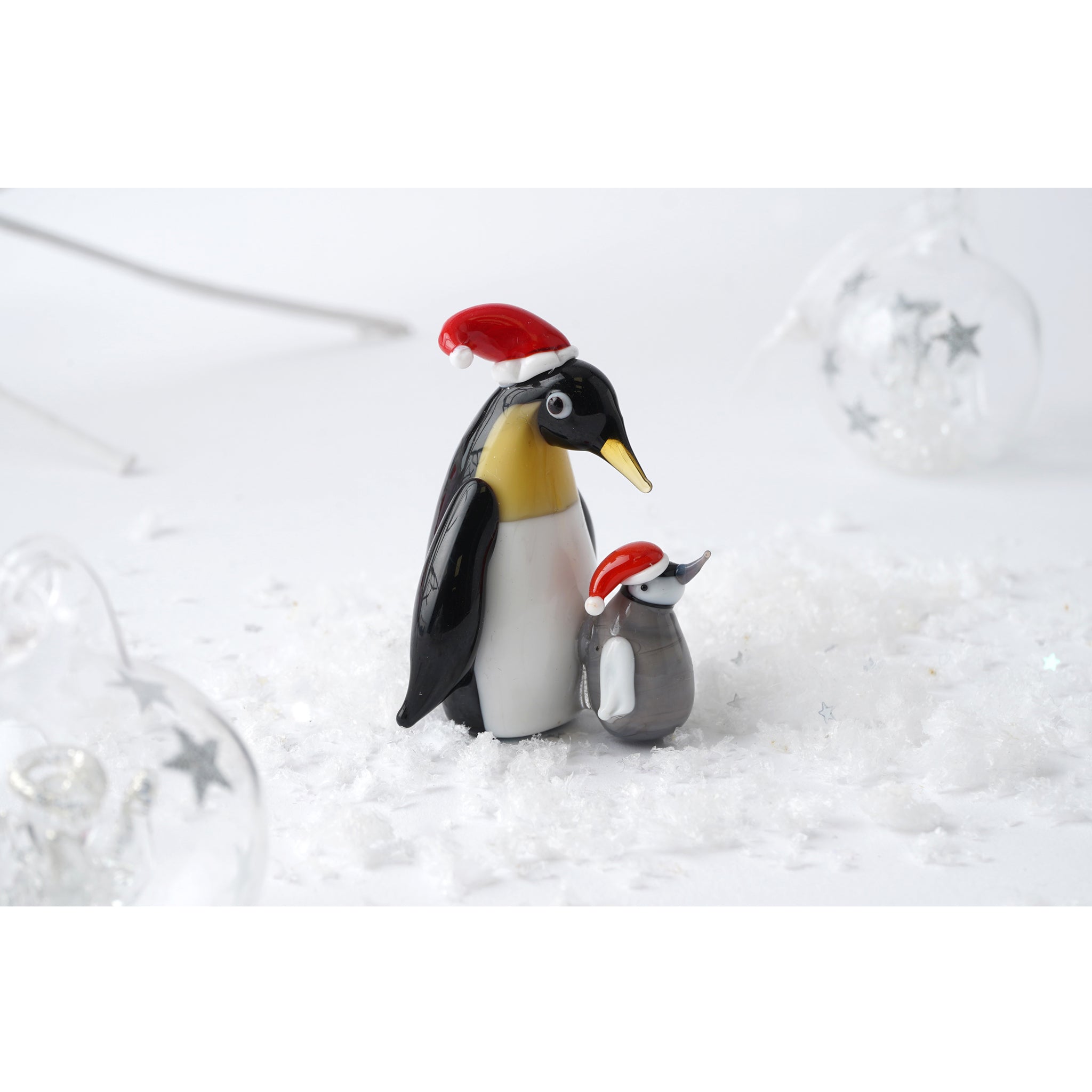 A glass figurine ornament with a parent and baby penguin in Santa hats lifestyle