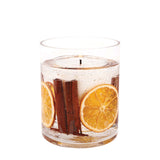 A tumbler candle with seasonal orange slices and cinnamon sticks in a clear gel