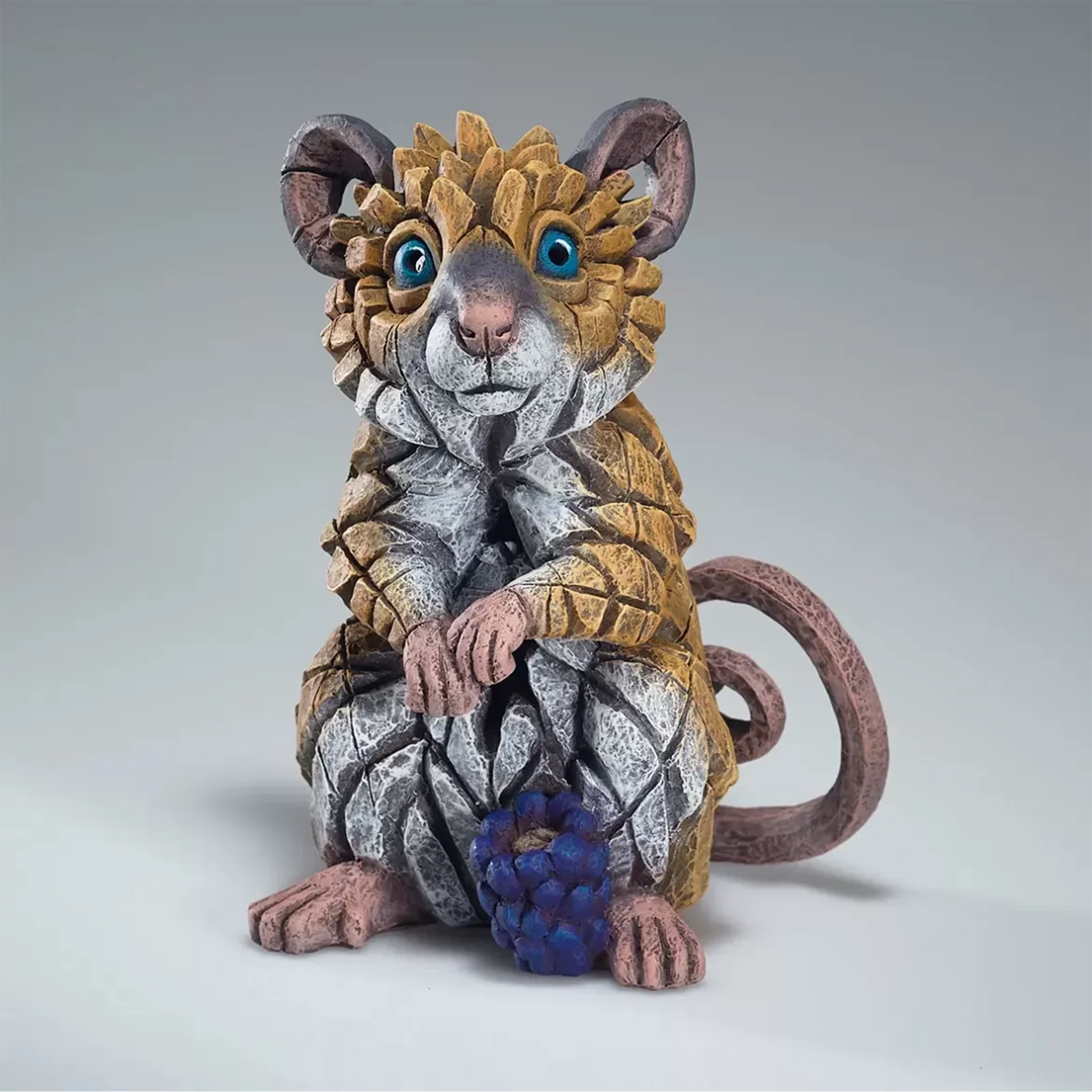 A painted sculpture of a field mouse with a little blackberry