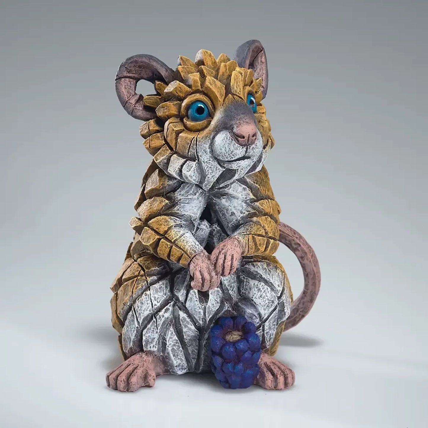 A painted sculpture of a field mouse with a blackberry