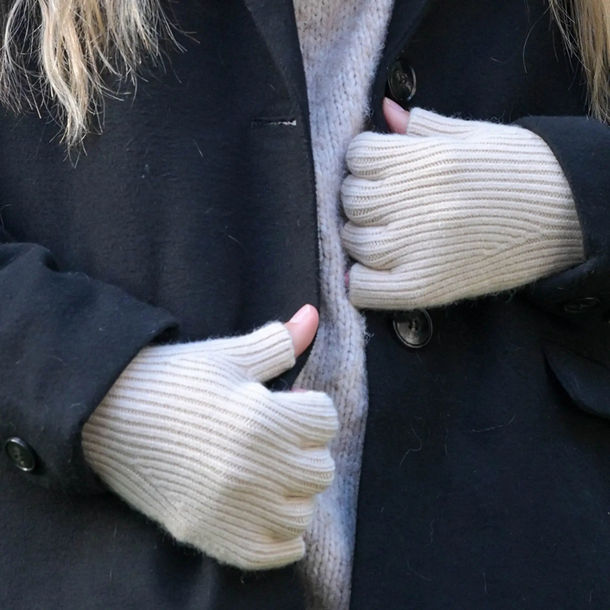 Model wearing a pair of cream coloured fine knitted fingerless gloves