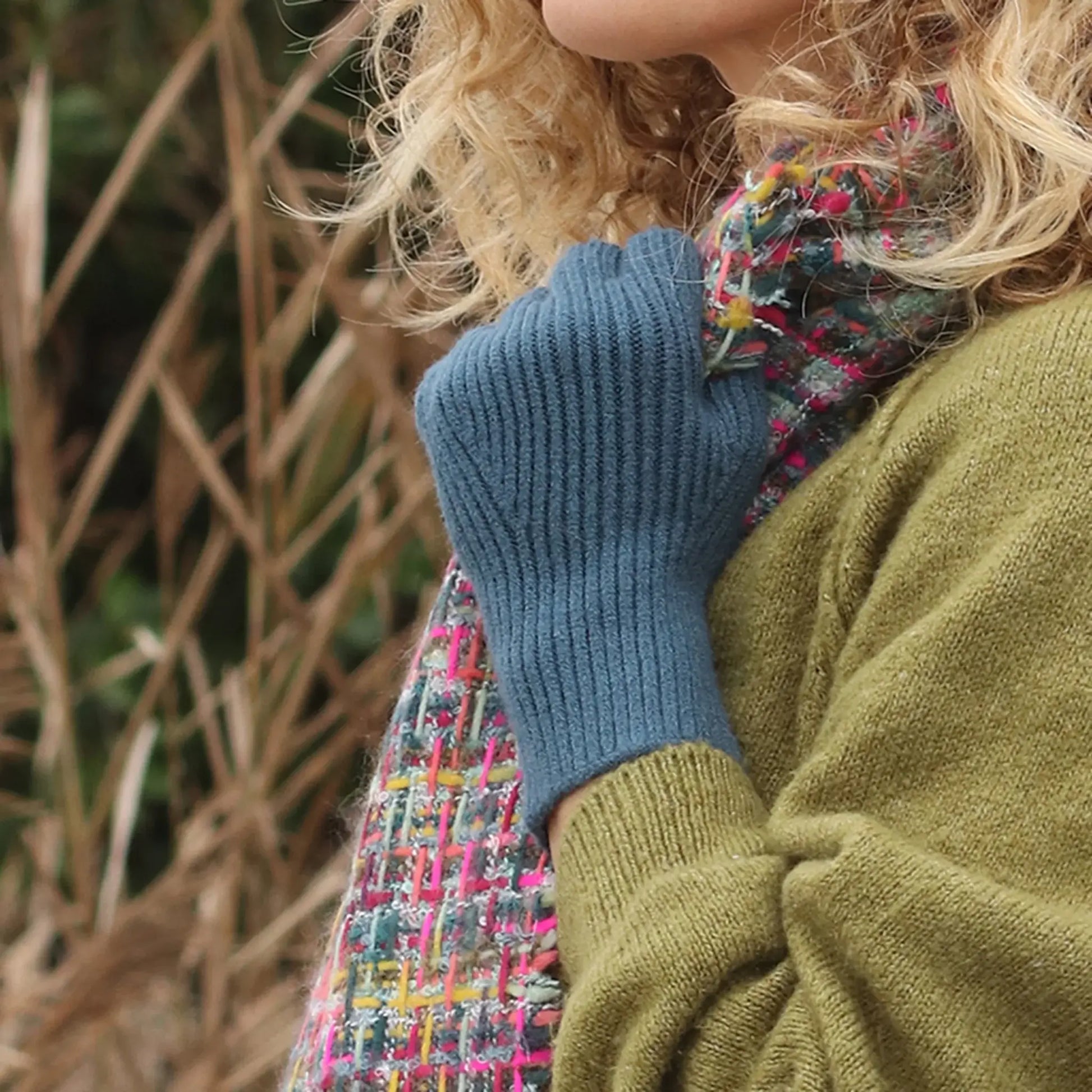 Model wearing pair of blue coloured fine knitted fingerless gloves