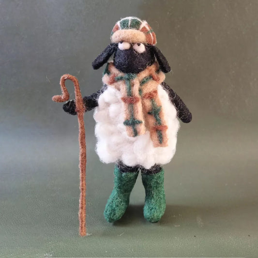 A felted sheep figurine with a hat, scarf and walking cane
