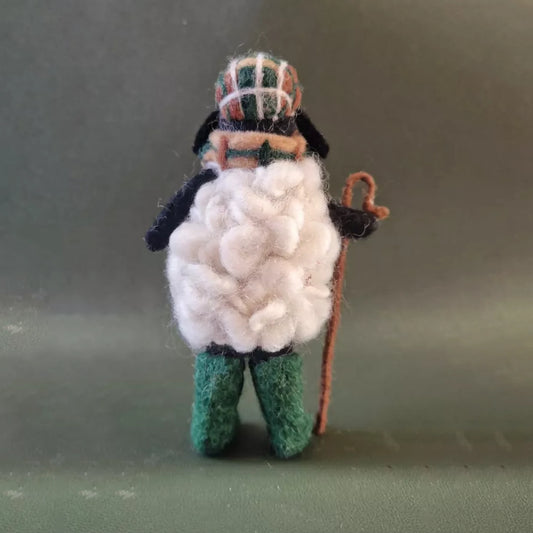 Back of a felted sheep figurine with a hat, scarf and walking cane