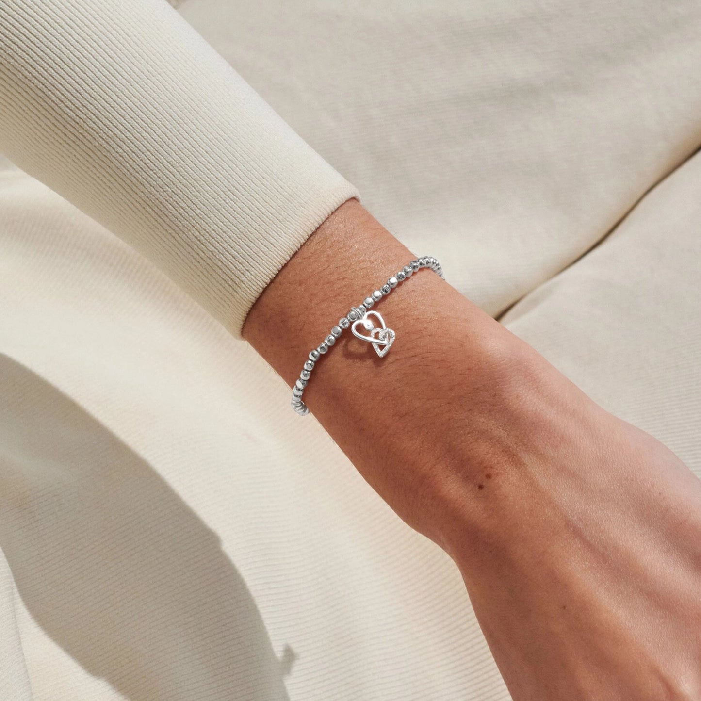Model wearing silver bracelet with two interlinked hearts in silver and CZ