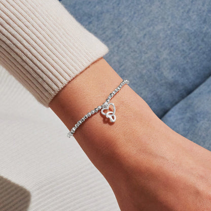 Model wearing silver stretch beaded bracelet with two interlocked hearts