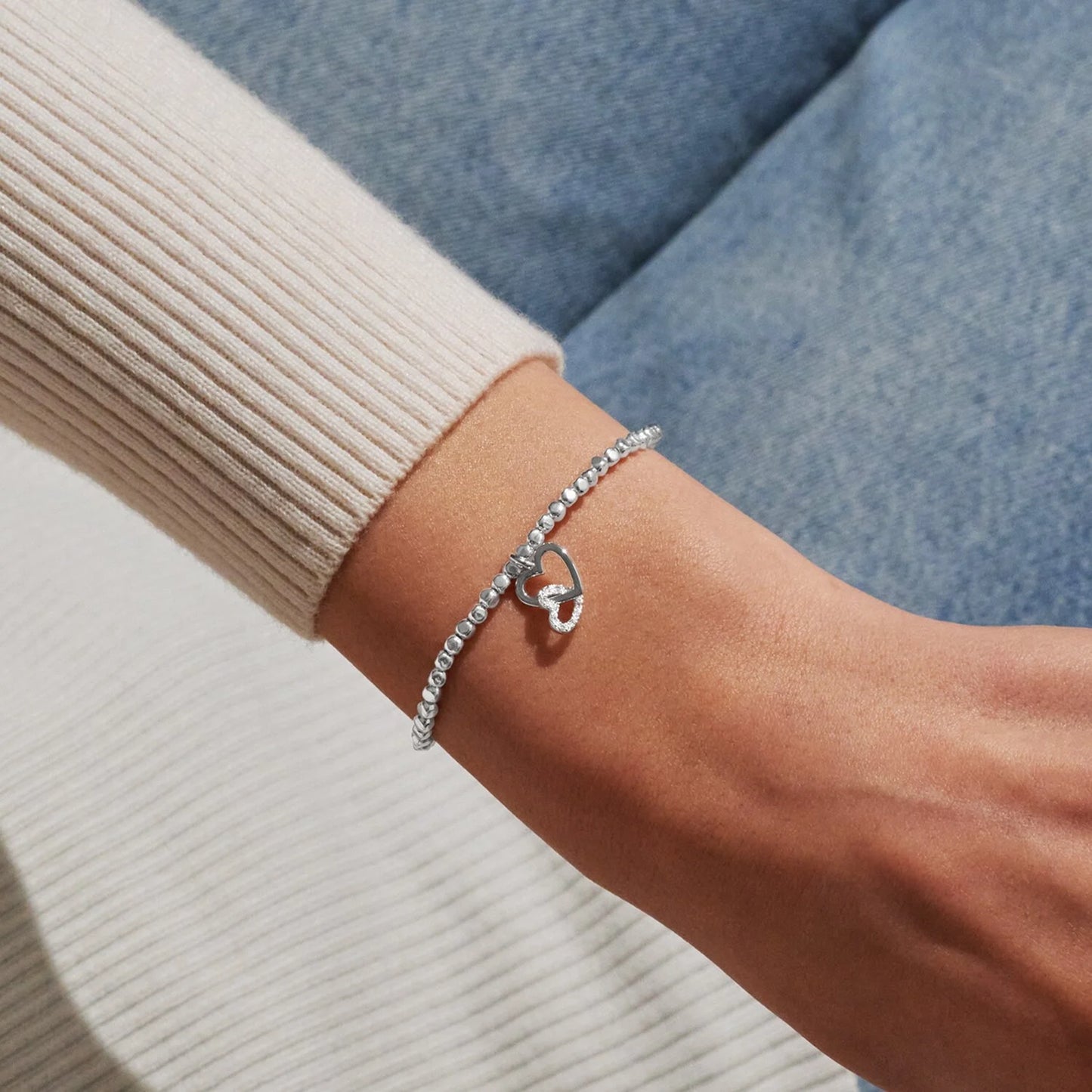 Model wearing silver bracelet with two interlinked hearts in silver and CZ