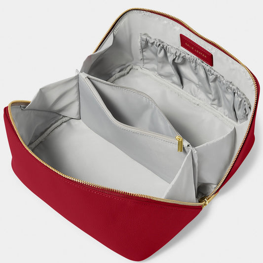 An open PU make-up bag in a bright red colour with various compartments and wipeable grey interior