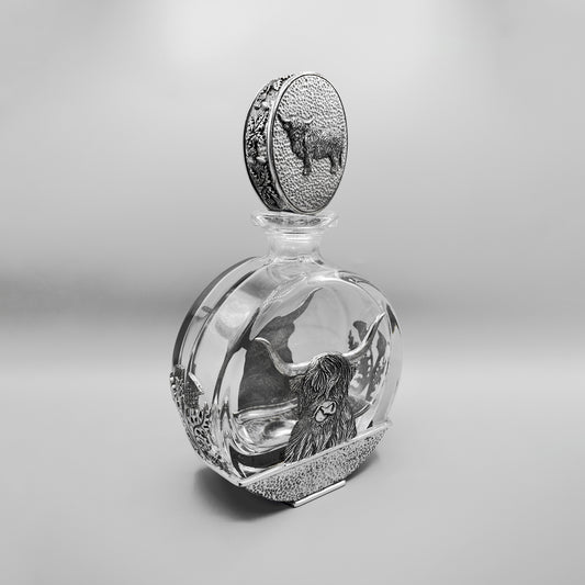 Side view of a glass decanter with pewter Highland cow oval stopper and Highland cow design on the base