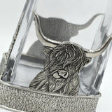 A glass decanter with pewter base featuring a Highland cow, and matching pewter stopper detail