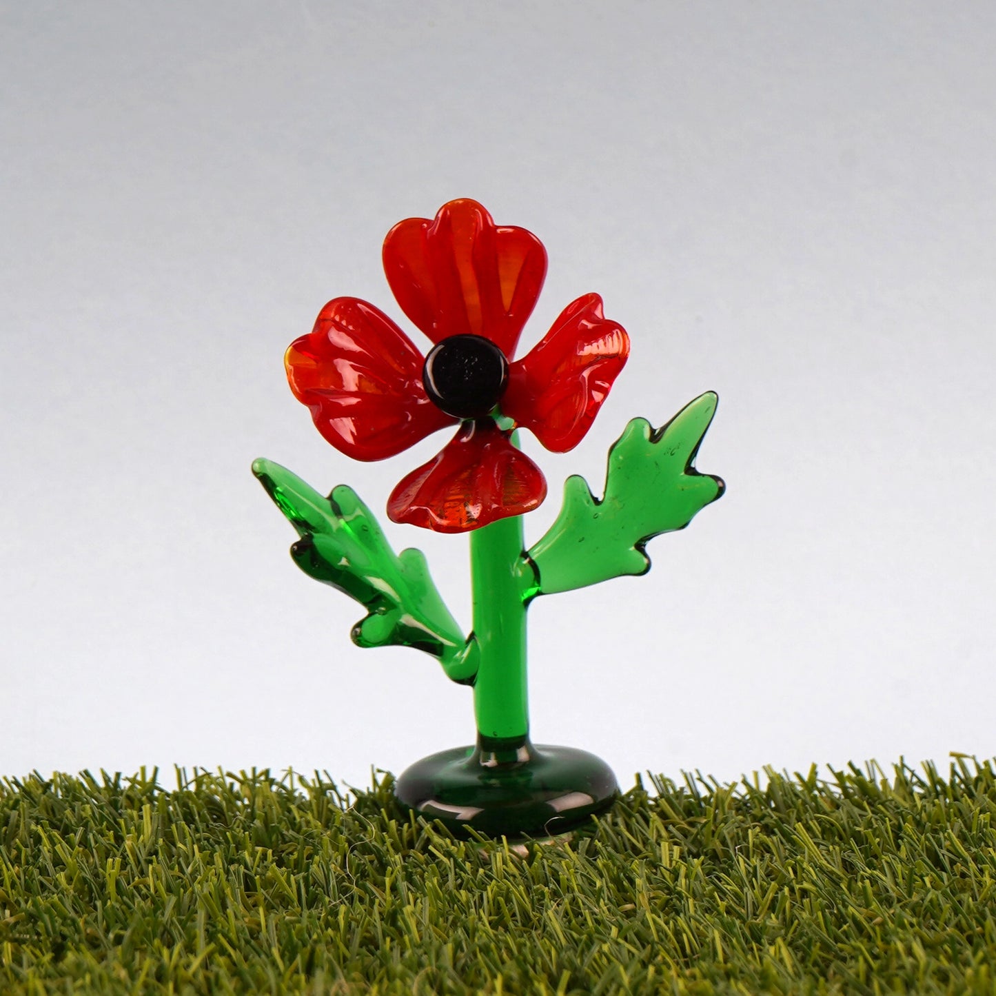 Glass red poppy figurine on faux grass