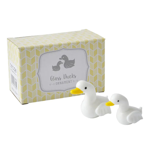 A pair of white glass duck ornaments with yellow beaks