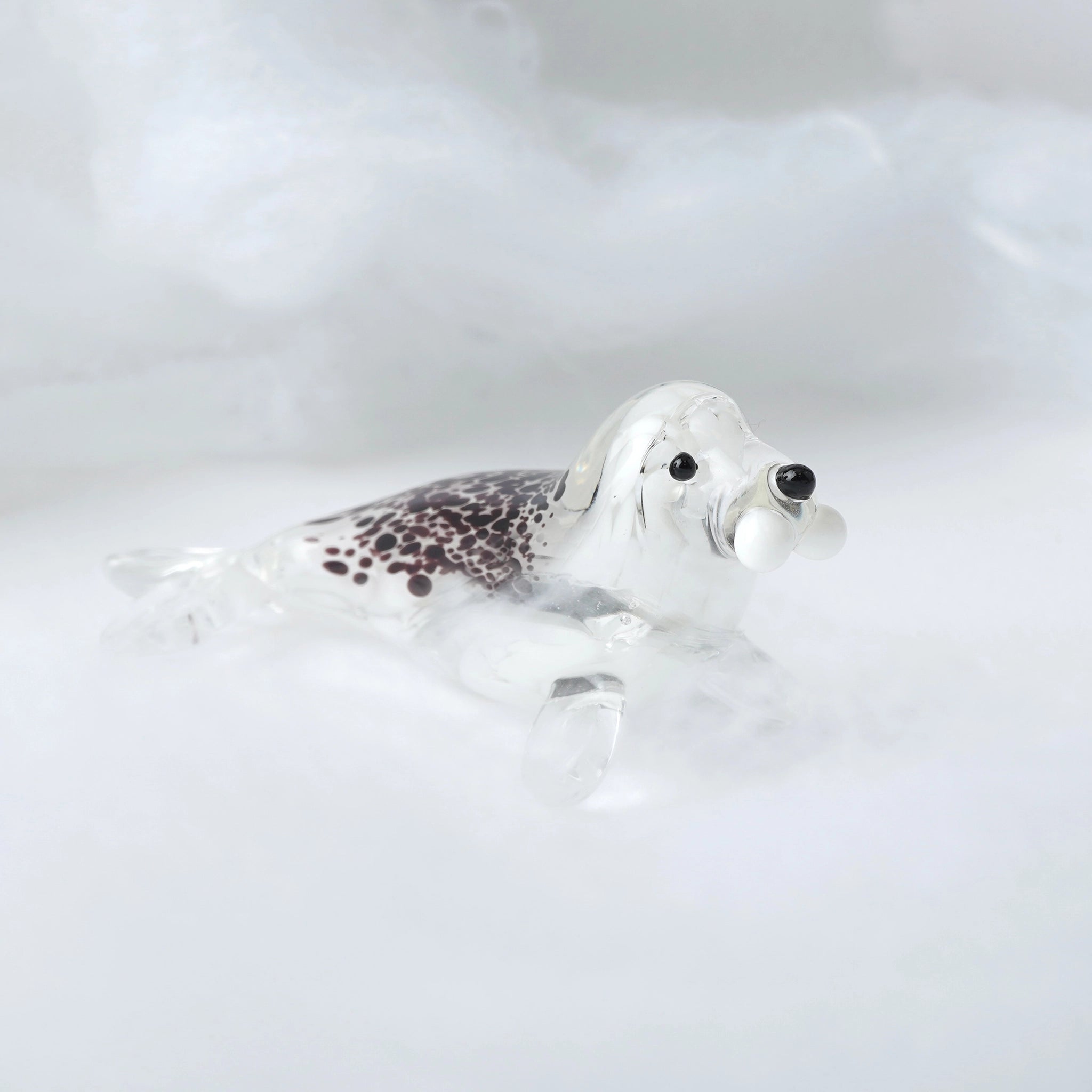 A speckled glass seal ornament in brown, clear and white