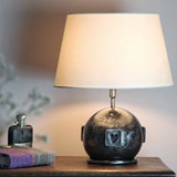 A globe shaped table lamp in a dark polished steel with a cream shallow drum shade