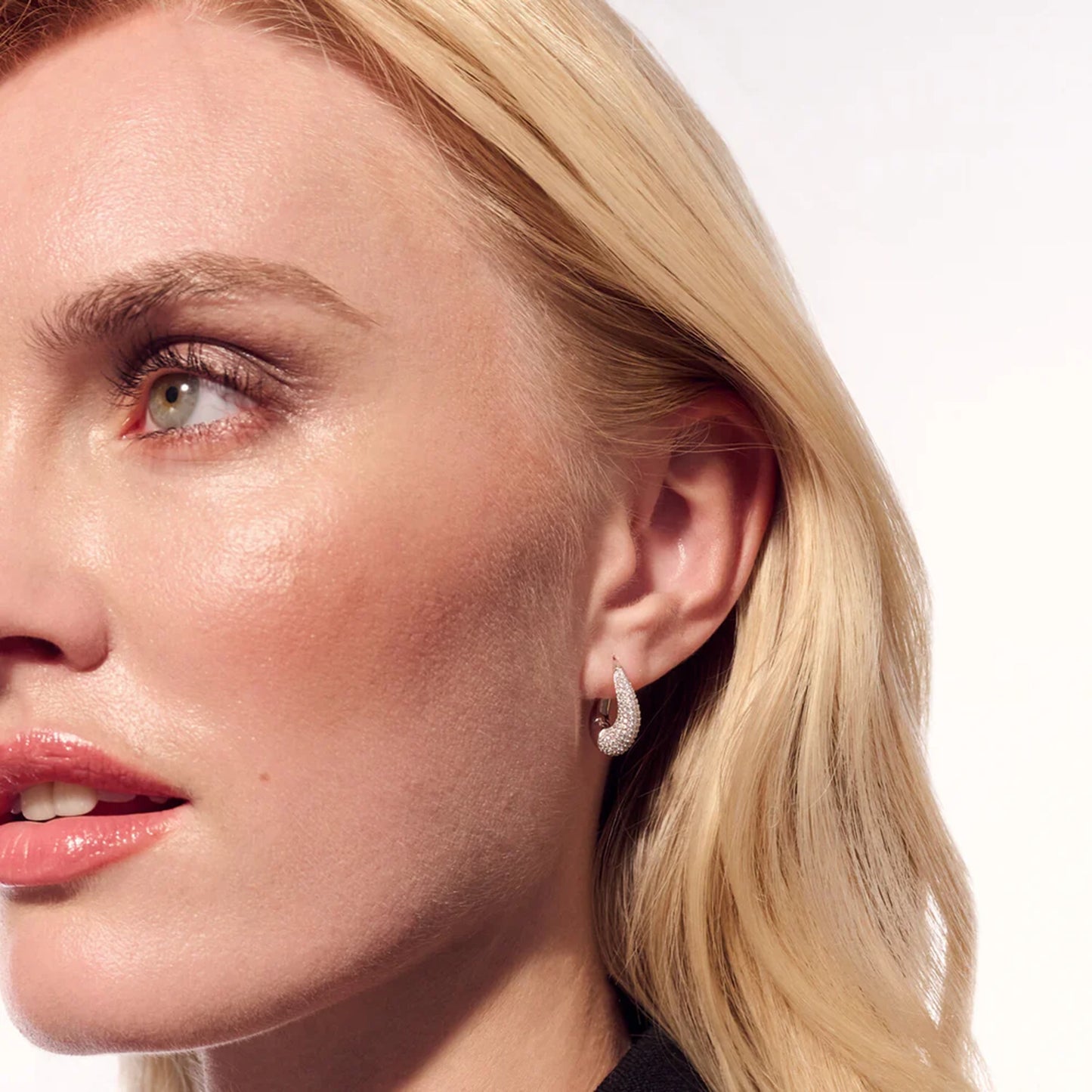 Model wearing a pair of chunky wave hoop earrings with CZ stones