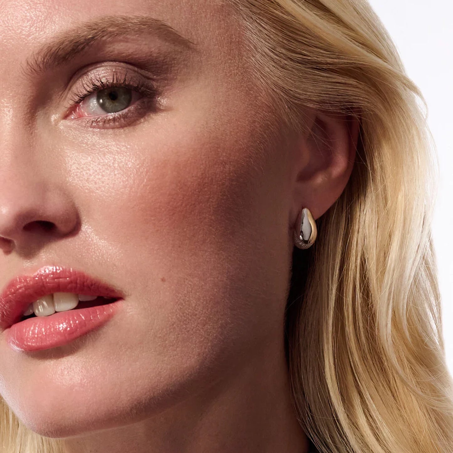 Model with pair of curved silver stud earrings with bevel in the centre and CZ stones at the base