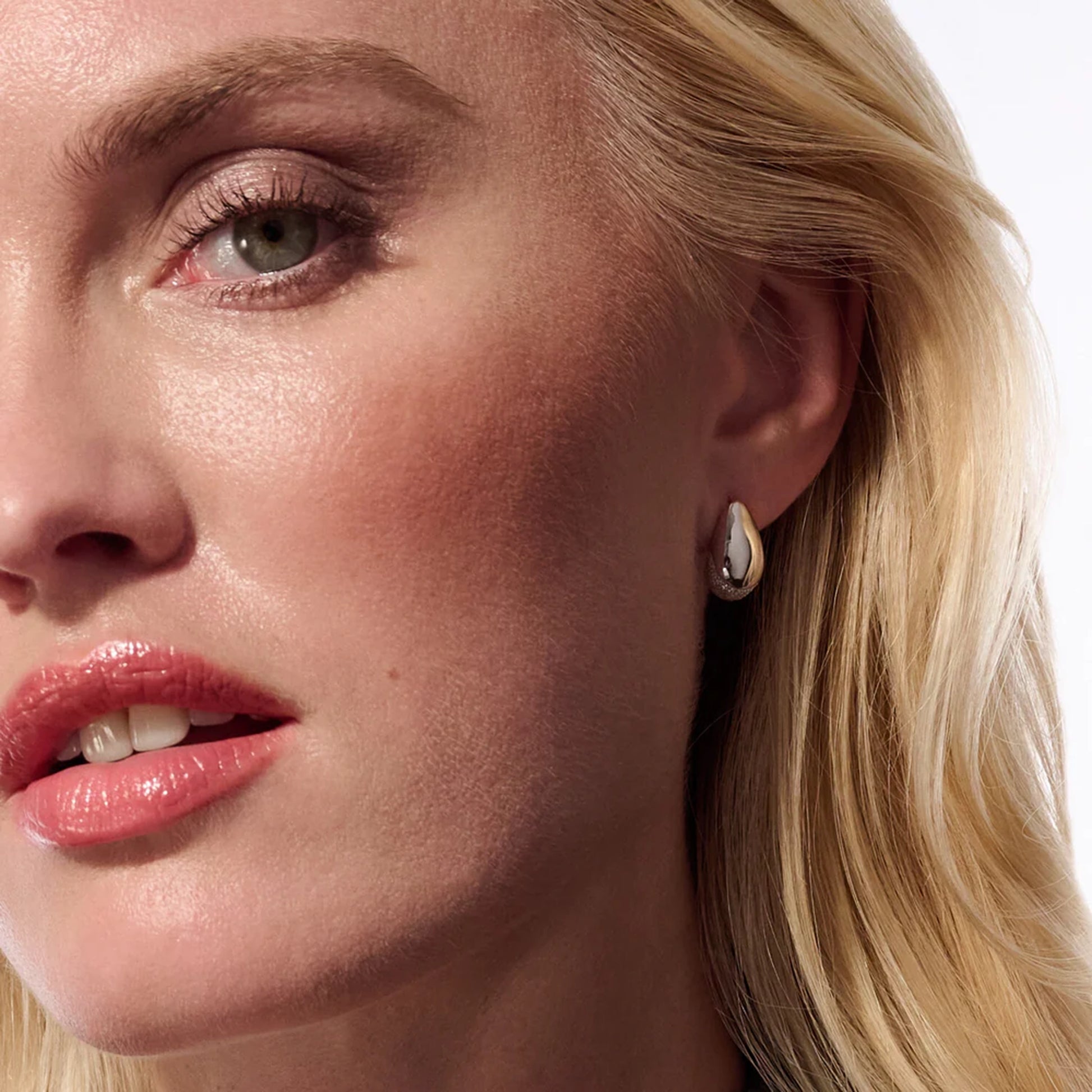 Model with pair of curved silver stud earrings with bevel in the centre and CZ stones at the base