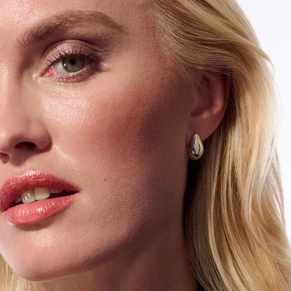 Model with pair of curved silver stud earrings with bevel in the centre and CZ stones at the base