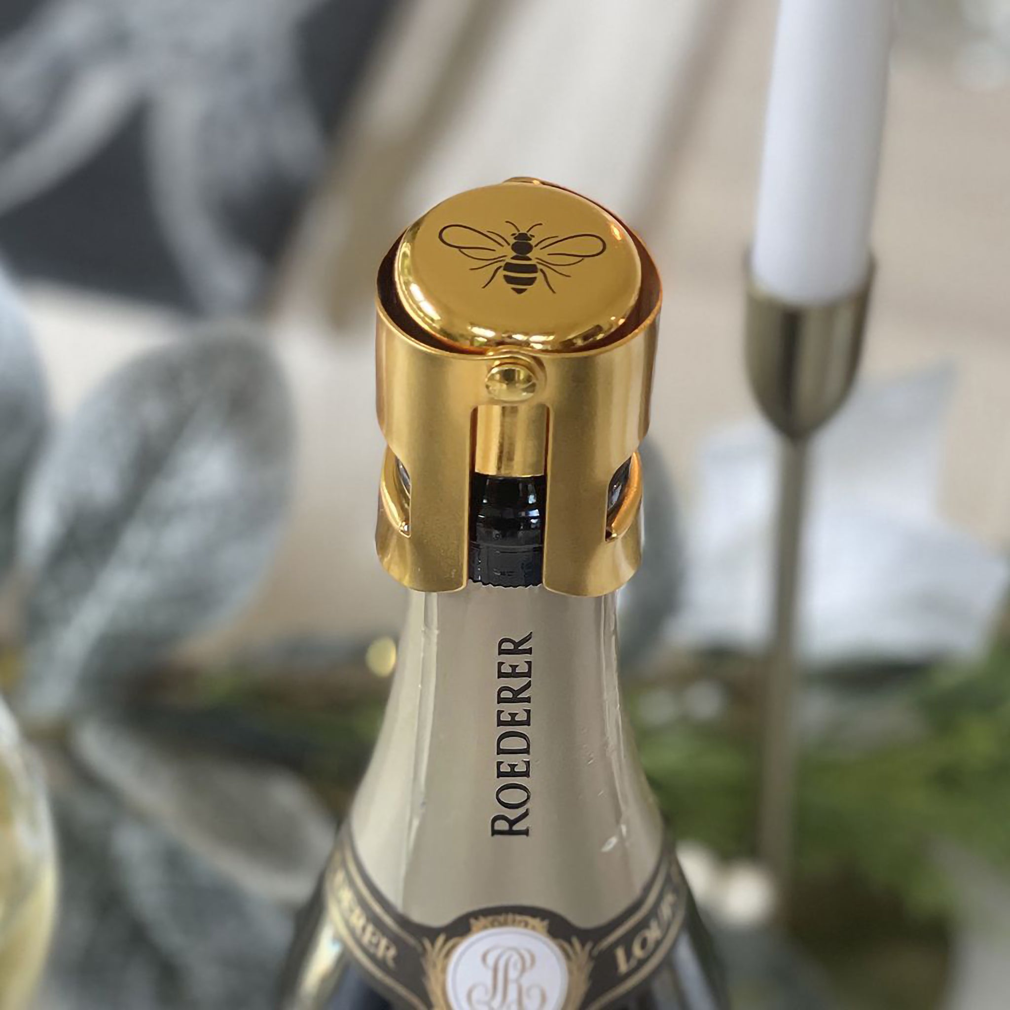 Gold prosecco stopper with black bee design on top on a bottle of champagne