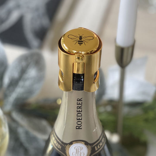 Gold prosecco stopper with black bee design on top on a bottle of champagne