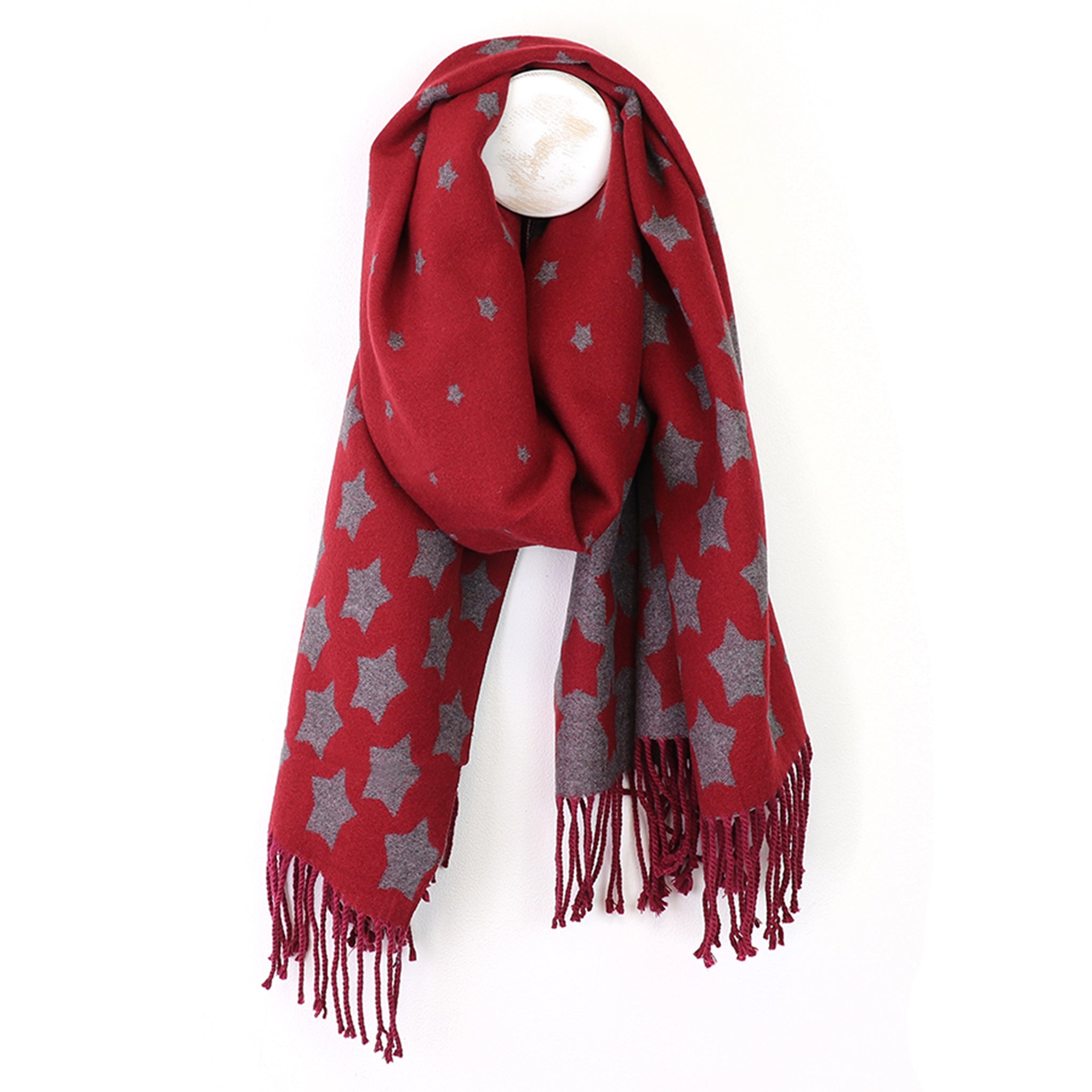 A red scarf with tassel trim and graduated sized grey star  pattern