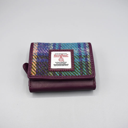A purple faux leather purse with genuine Harris Tweed plaid in the front