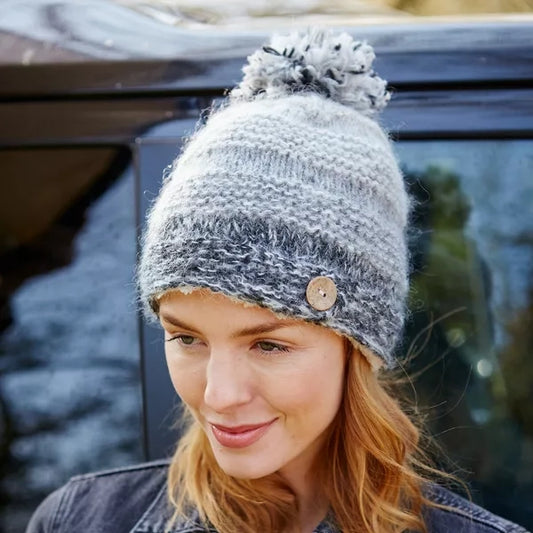 Model wearing a grey ombre fluffy knitted pompom hat with button detail