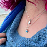 Model wearing Polished silver groatie buckie shell pendant on silver chain stacked with a small pentland necklace