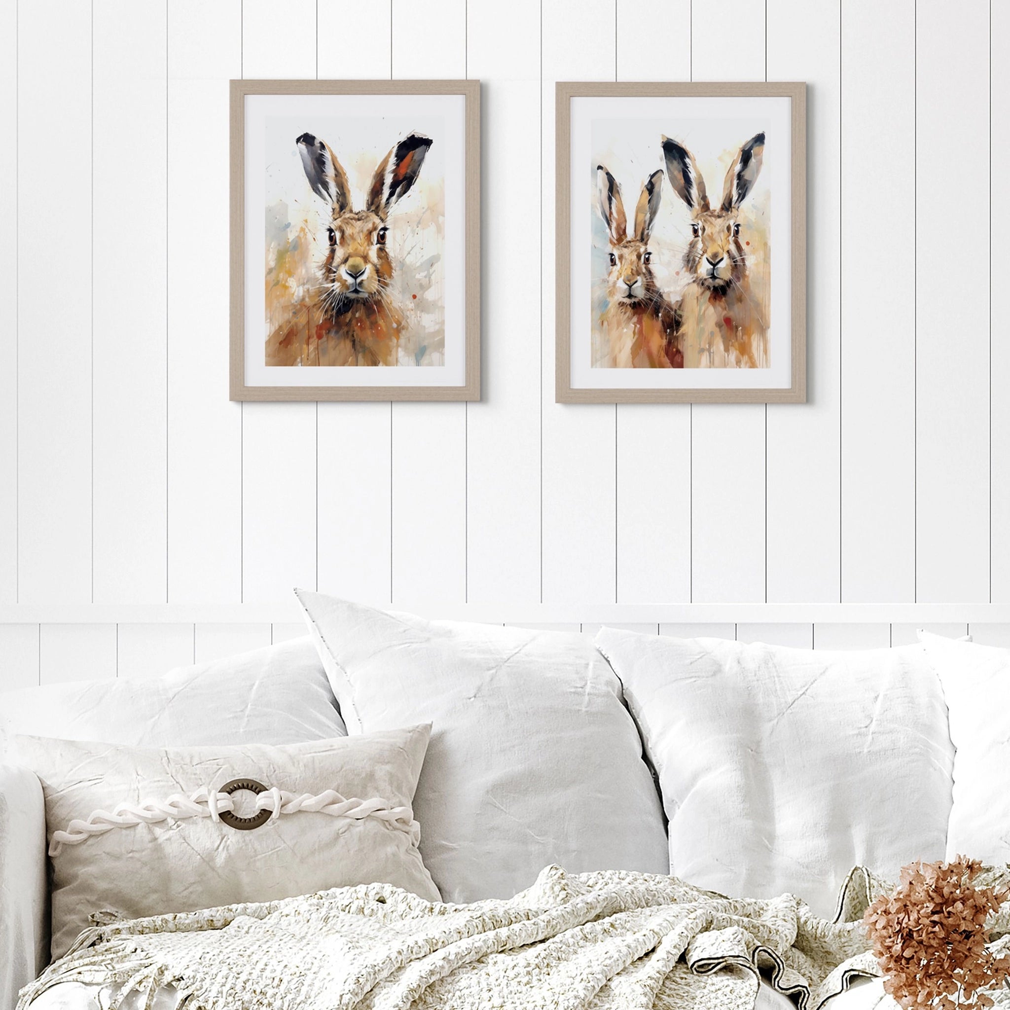 A wall art print of two hares in a neutral palette and wood effect frame hanging