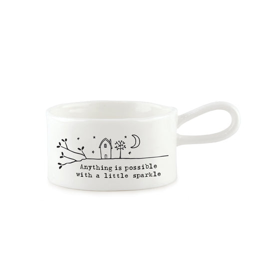 A white handled tealight holder featuring a little house illustration and a quote 