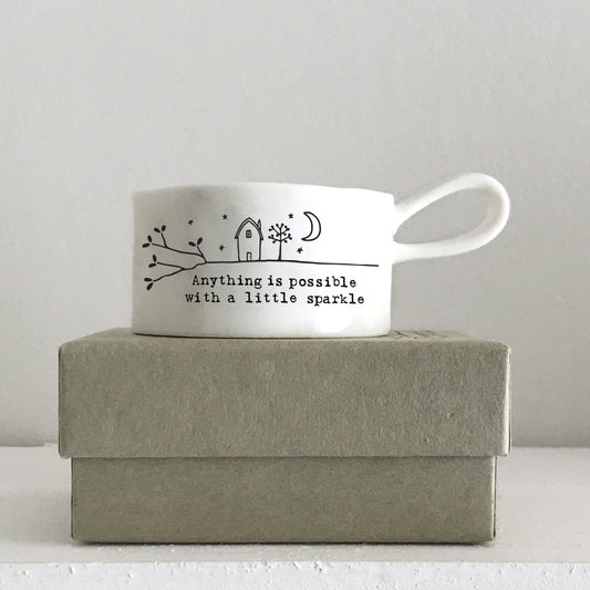A white handled tealight holder featuring a little house illustration and a quote on a box