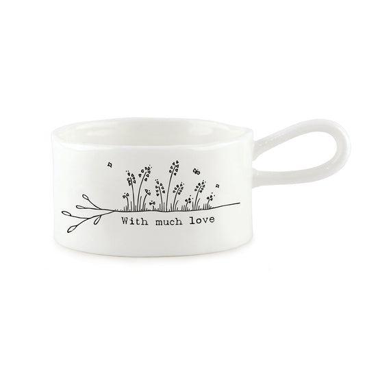 A white handled tealight holder featuring a little flower illustration and a quote